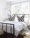 Wrought iron bed in white bedroom in front of window