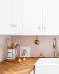 A small kitchen with a pink backsplash and a collapsible dish rack