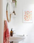 A white half bath with minimalist decor and a hanging plant