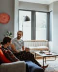 Couple sitting on a blue sofa in a cozy living room with a fireplace, TV, and modern decor.
