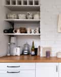 A clutter free kitchen with white walls and open shelving.