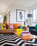 Living room with brown and black sofas, colorful pillows, zigzag rug, and modern art on walls.