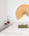 Bed with white bedding, green pillow, and large fan-shaped wall decor above.