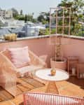 Rooftop patio with pink wire chair, cactus, and potted plants; poolside area with striped curtains and a black dog.