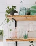 Wood shelves with glassware by exposed brick wall