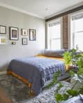 Light-filled modern bedroom in a loft apartment with brick wall and abstract art and modern colorful furniture.