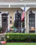 Two adjacent houses with Halloween decor, including witch hats, bats, pumpkins, and an American flag.