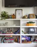 A white bookshelf full of books and eclectic decor