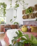 Bedroom with hanging plants, woven wall baskets, colorful pillows, and a patterned rug, creating a cozy, bohemian vibe.