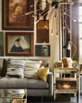 Cozy living room with a gray sofa, textured pillows, eclectic wall art, a vintage side table, and a modern chandelier.