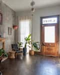 Room with a piano, framed photos, fireplace, plants, and a wooden door.
