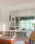 Living room with a patterned daybed, yellow chair, large mirror, and plants.