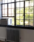 Room with black-framed windows, radiator, air conditioner, and checkered floor.