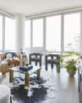 A living room with floor-to-ceiling windows, a leather couch, and a square coffee table