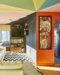Colorful living room with a cream sofa, zigzag rug, wall art, and large windows.