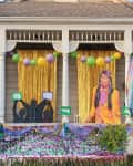 House decorated for Mardi Gras with colorful balloons, gold curtains, and festive cutouts on the porch.
