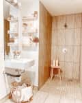 Modern bathroom with a walk-in shower, wooden shelves, white sink, and decorative plants.