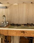 Rustic kitchen with a metal sink, two-burner stove, and wooden cabinetry, marked "Before" in red.