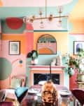 Colorful dining room with abstract wall art, a piano, round table, velvet chairs, plants, and a modern chandelier.