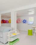 Basement playroom with gray sofa, colorful flower wall art, round table, and modern decor.