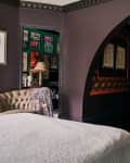 A purple bedroom with a curved wall; a different section of the room features black walls and a hexagon angled wall with a mirror