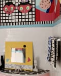 Colorful bathroom with geometric wall art, a yellow mirror, and eclectic decor including cat and rabbit figurines.