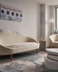 Two cream sofas in a living room with a round white coffee table, floor lamp, and a window view of skyscrapers.