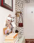 White entryway with black cow spot wallpaper and lots of small shelves and hooks