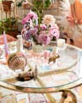A glass coffee table with flowers and candles on top