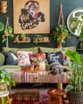 Eclectic living room with green sofa, colorful pillows, lush plants, and wall art saying "Keep Growing."
