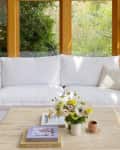 White sectional and square-shaped coffee table in room with large windows