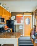 Kitchen with wooden cabinets, granite countertop, black appliances, fruit bowl, and bookshelves along the wall.