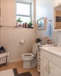 A small bathroom with a window and decor on the ledge