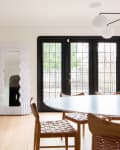 A mirror in a white, wavy frame standing next to French doors in a light-filled dining room