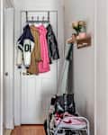 White entryway with coats and jackets hanging, a shoe rack, and small wall hooks