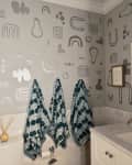 A bathroom with a funky mural and patterned hanging towels.