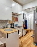 Modern kitchen with white cabinets, subway tile backsplash, wooden floor, and a small dining table with two chairs.