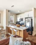 Open-plan kitchen and dining area with white cabinets, stainless steel appliances, round table, and modern decor.