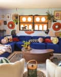 Colorful living room with blue sectional sofa, eclectic decor, plants, and abstract wall art.