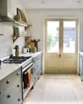 Galley kitchen with gray cabinets, white countertops, open shelves, and a large range cooker near double doors.