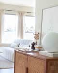 A white and cream living room with a curvy couch and a rattan foyer table