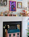 Colorful playroom with a white mantel, decorative toys, artwork, and a small table with chairs.