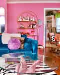 colorful living room with some pink walls, some white, pink front door, blue velvet sofa with colorful throw pillows, arched deco mirrors, lots of colorful framed wall art
