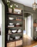 Arched entry ways in neutral kitchen with gray-green walls, wood floors and open shelving