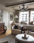 Dark ornate wood sideboard and cream colored couch in front of a large window in neutral living room