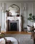 White fireplace, brown sueded armchair and white dresser in neutral colored living room