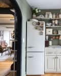 Kitchen with grey-green walls, open shelving, hardwood floors and hexagonal tile