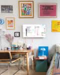 Colorful artwork hung on bedroom wall in studio apartment with colorful neatly made bed.