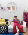 Dweller seated on sofa in colorful studio apartment.