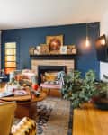 Blue/grey sofa in living room with blue accent wall near yellow to orange ombre glass entry door. Cord pendant light bulb hung in the corner.